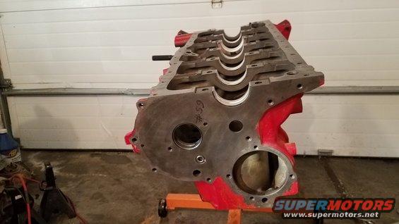 Engine block on an orange stand in a garage. Some red paint is visible on the block