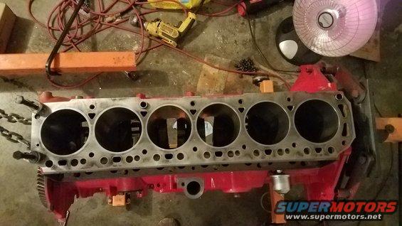 Engine block with six cylinders, red painted block, metal chains attached