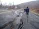 1979 Ford Bronco - A damaged road with large cracks and debris, with three individuals observing the scene in snowy weather.