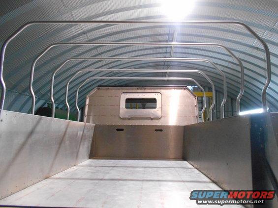 Interior of a custom aluminum truck bed with a roll cage inside a metal building.