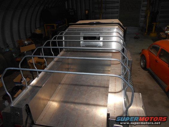 Custom aluminum structure with railings in a workshop, with an orange VW Beetle nearby.