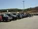 1995 Ford Bronco - Several SUVs and trucks are parked in a lot on a sunny day, with a group of people gathered.