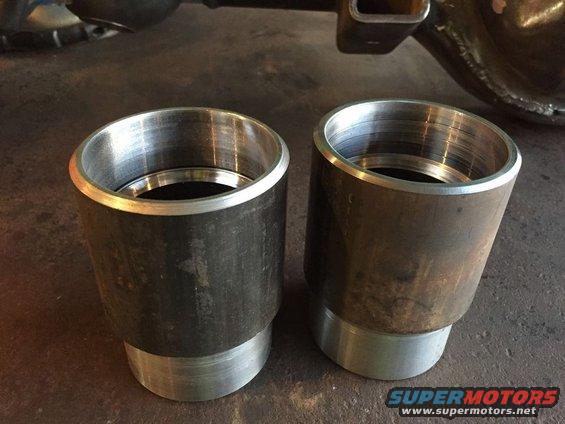 Two metal exhaust tips with threaded interiors, one slightly larger than the other, resting on a concrete surface