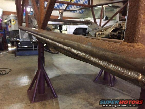 Welded metal frame section supported by purple jack stands in a garage