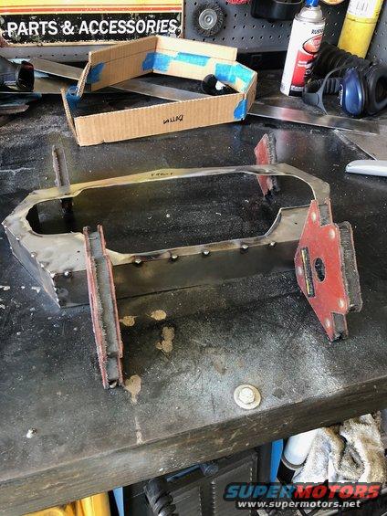 Metal frame being worked on a workbench with tools and a cardboard template