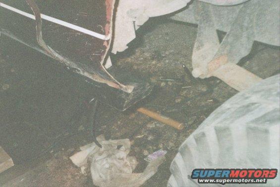 close-up of vehicle's tire and frame, with debris on the ground