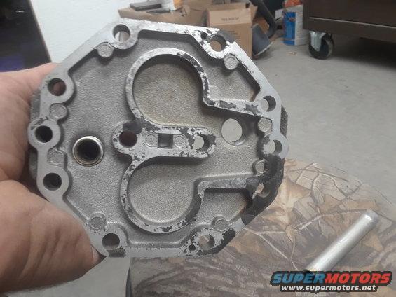 Metal part held in hand, showing circular openings and bolt holes