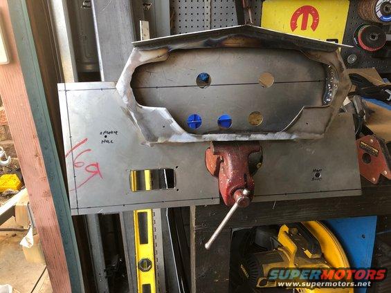 Custom metal dashboard panel being fabricated, held in a vise. Some handwritten notes and cutouts are visible