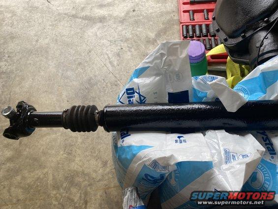 Driveshaft with U-joint and rubber boot, resting on bags