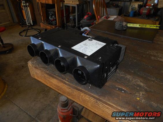 Black HVAC unit with multiple vents on a wooden workbench.