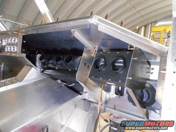 Interior view of vehicle HVAC system with aluminum panels and black ducting.