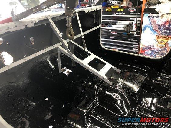 Interior of a vehicle with black painted floor and a metal frame overhead