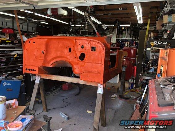 Orange Jeep CJ-7 tub on sawhorses in a garage