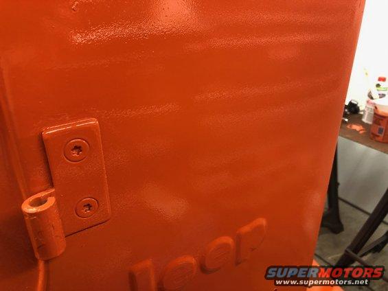 Freshly painted orange Jeep body panel with embossed Jeep logo and hinge