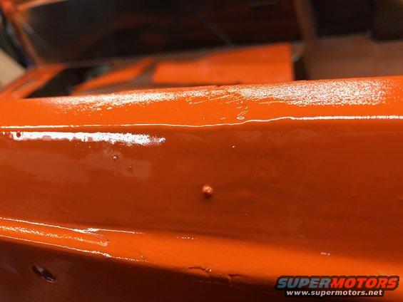 Close-up of orange painted metal with some imperfections and a watermark