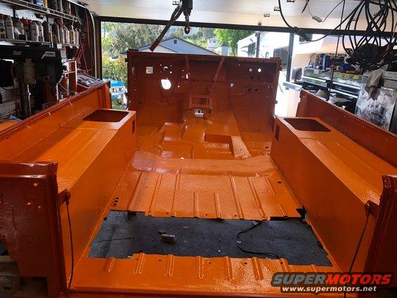 Jeep CJ tub interior painted bright orange, showing floor pan and seat mounts