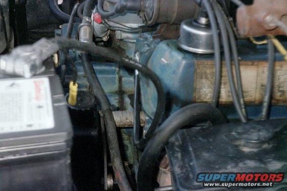 Engine bay detail showing battery and engine components. Text on battery is partially visible