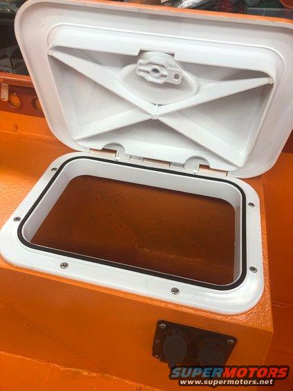 Open white hatch on orange boat interior, showing dark contents