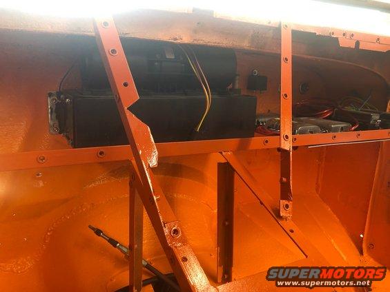 Interior of a vehicle with orange paint, showing wiring and a black box