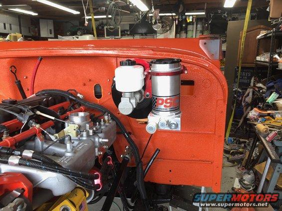 Jeep engine bay with orange firewall, showing power steering pump and brake fluid reservoir
