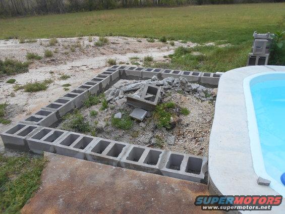Cinder block foundation for a structure next to a swimming pool, with debris in the center