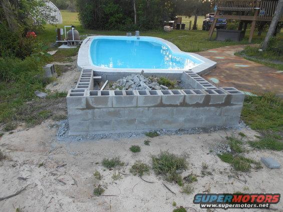Swimming pool construction with cinder block wall and pool equipment visible
