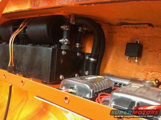 Orange interior with black electrical components, hoses, and fuse boxes