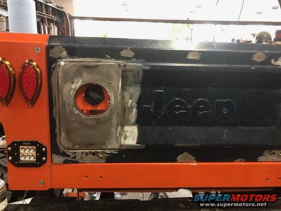Orange Jeep tailgate with "Jeep" embossed and bodywork around fuel filler