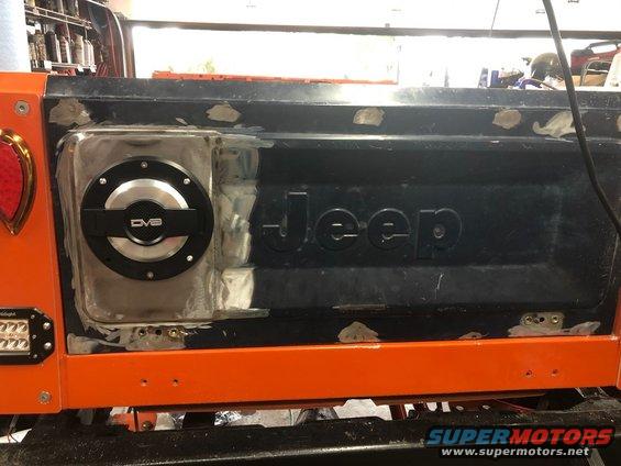 Jeep tailgate with "Jeep" embossed, a circular DVB fuel door, and orange bumper