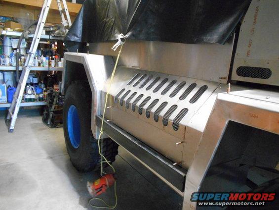 Side panel of custom vehicle with diamond-pattern vents and blue wheel rim