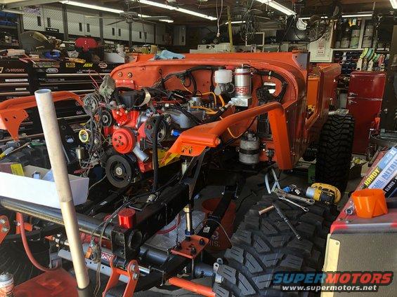 Orange Jeep Wrangler chassis with engine installed, front view