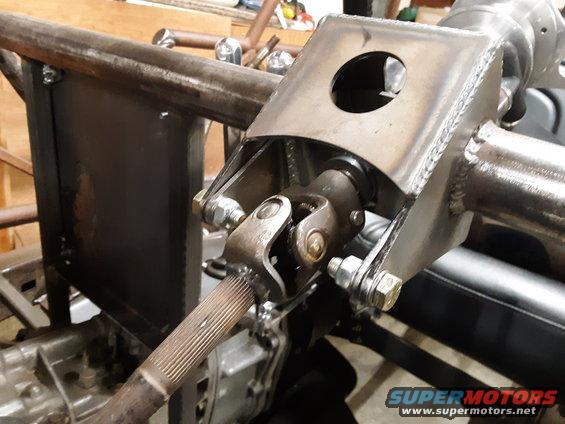 Steering column universal joint attached to a custom metal bracket, with part of a gearbox visible