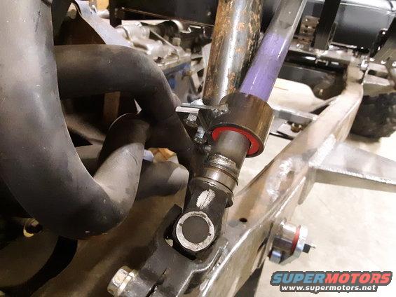 Close-up of vehicle frame with exhaust pipes and a purple-colored shaft with red bushings