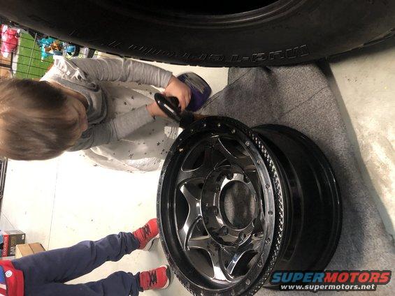 Child cleaning a chrome wheel with a power tool