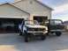 1979 Ford Bronco - A 1978 Ford Bronco is parked next to a pickup truck undergoing repairs in front of a garage.