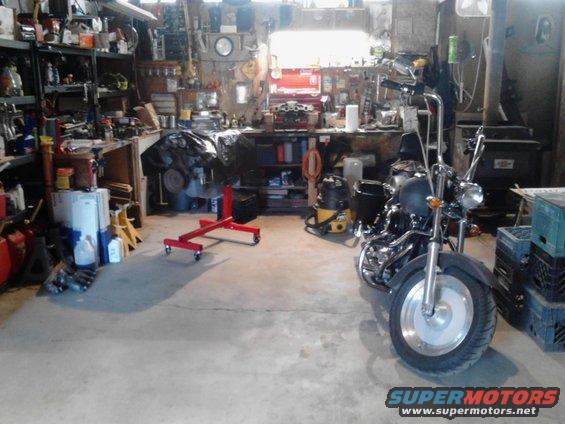 Motorcycle parked in a cluttered garage with tools and engine parts around