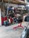 1978 Ford Bronco - An engine is mounted on a red stand in a cluttered garage workshop.