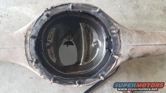 Open differential housing with some oil inside. It looks like the cover has been removed