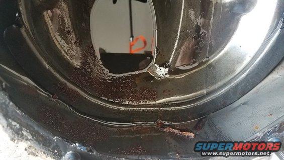 Differential cover with dark fluid and rust. A reflection shows an orange object