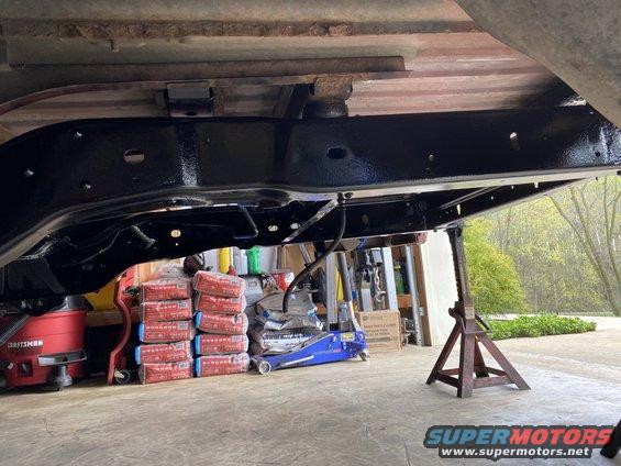 Vehicle frame on jack stands with a blue floor jack and red Craftsman shop vac