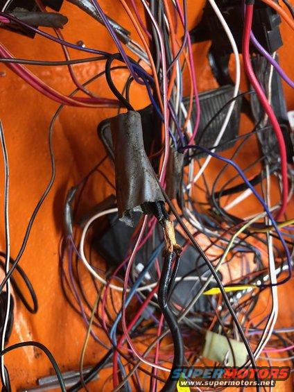 Tangled vehicle wiring harness with frayed black wire and orange interior paneling