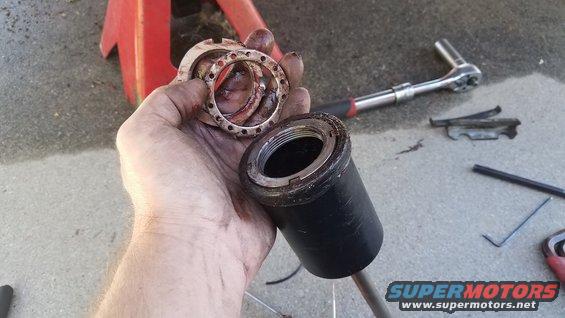 Hand holding a black part with a red top, possibly a tool