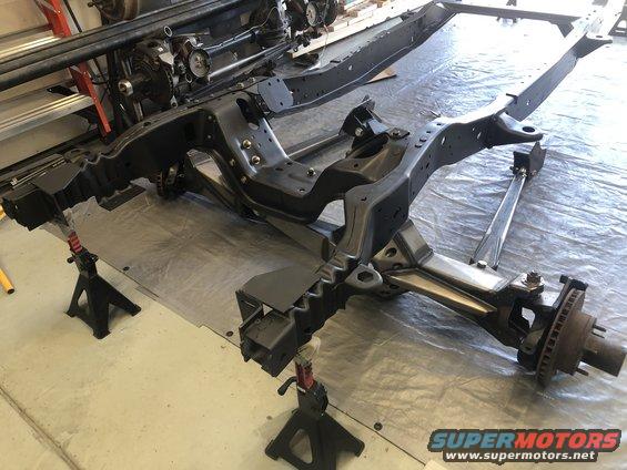 Black vehicle frame on jack stands, front suspension visible