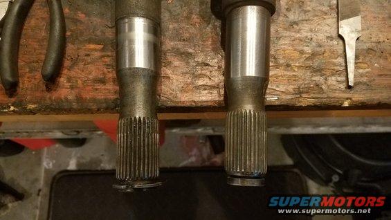 Two splined axle shafts resting on a wooden workbench with tools nearby