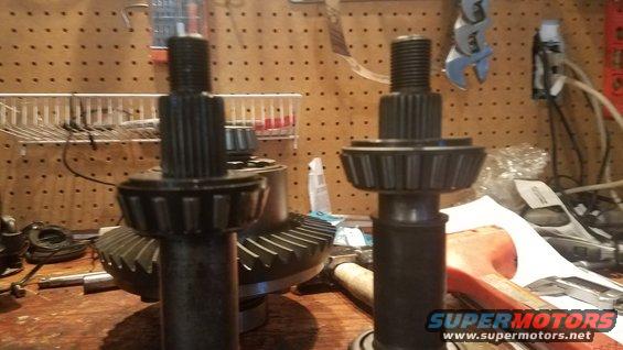 Two differential pinion shafts and a ring gear on a workbench