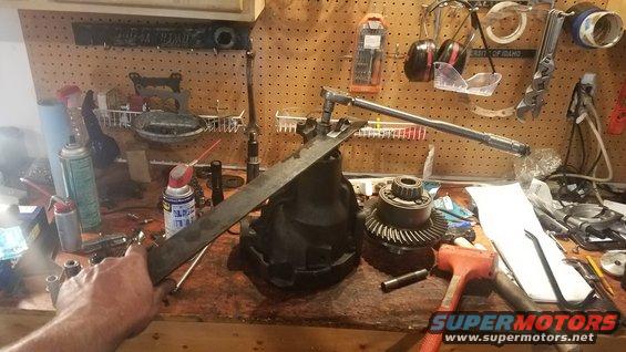 Differential and gears on a workbench with tools, including a torque wrench and hammer