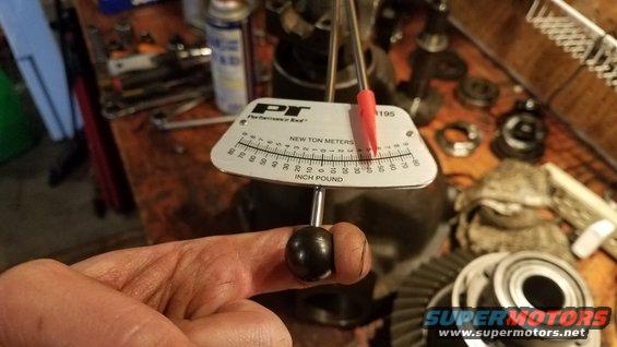 Hand holding a torque wrench over differential gears and bearings