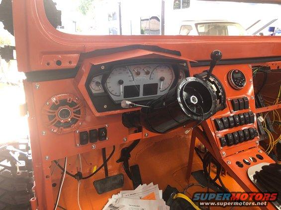 Custom dashboard with aftermarket gauges and numerous switches. Steering column is visible