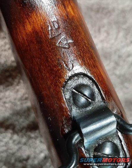 Close-up of wood stock with stamped markings and metal hardware attached