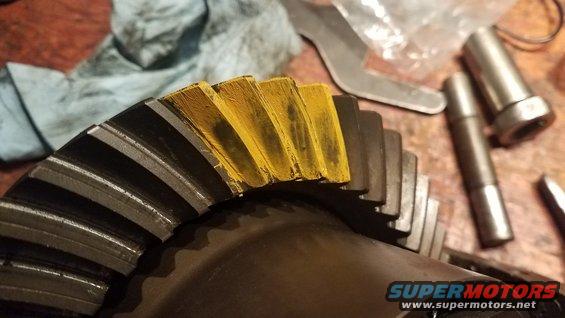 Close-up of a differential ring gear with yellow marking compound on the teeth